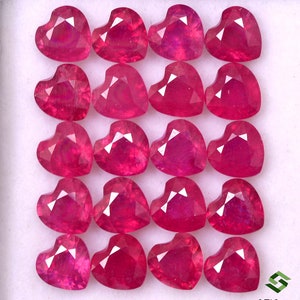 May include: A collection of 18 heart-shaped ruby gemstones, each with a deep red hue and a faceted cut. The gemstones are arranged in a grid pattern on a white background.