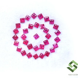 May include: A collection of square-cut, vibrant red gemstones arranged in a spiral pattern on a white surface. The gemstones are evenly spaced, creating a visually appealing design. The image is well-lit, highlighting the color and clarity of the gems.