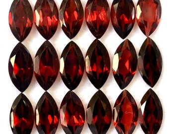May include: A collection of 18 maroon marquise-shaped gemstones. The gemstones are arranged in three rows of six, each row offset from the one above it.