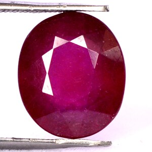 Puede incluir: Una piedra preciosa ovalada de color rojo intenso con un corte facetado.