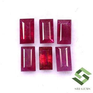 May include: Six rectangular ruby gemstones, each with a slightly different shade of red, are arranged in two rows of three. The gemstones are all cut in a similar style, with a slightly rounded edge. The gemstones are set against a white background.