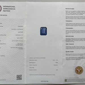 May include: A folded document from the International Gemological Institute, detailing a coloured stone report. The report includes the stone's specifications, such as weight (0.22 carat), measurements (4.10 x 3.16 x 1.70 mm), and colour (deep blue). A sapphire gemstone is shown.