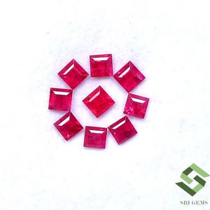May include: Nine vibrant red, square-cut gemstones arranged in a circular pattern with one stone centred. Each gemstone features faceted surfaces that reflect light. The text SBI GEMS and a green geometric logo appear in the bottom right corner.