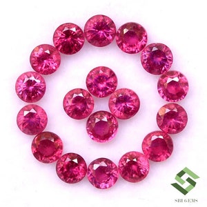 May include: A collection of 18 round, faceted, pink ruby gemstones. The gemstones are arranged in a circle on a white background.