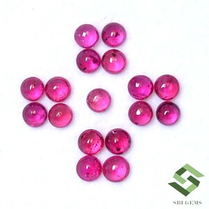 May include: A collection of 12 round, pink gemstones. The gemstones are arranged in a symmetrical pattern on a white surface.