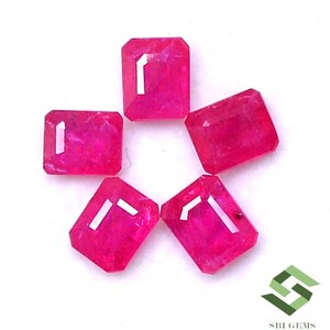 May include: Six pink emerald cut gemstones. The gemstones are arranged in a circle on a white background.