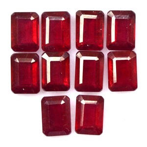 Puede incluir: Diez cabujones de piedras preciosas rojas, talladas en forma de esmeralda rectangular. Las piedras preciosas están dispuestas en dos filas de cinco, con la fila inferior ligeramente desplazada.