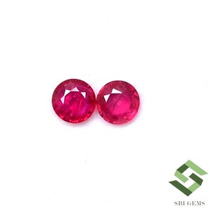 Puede incluir: Dos piedras preciosas redondas de rubí rojo. Las piedras preciosas son facetadas y tienen un acabado brillante y pulido.