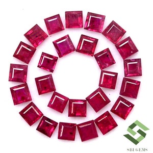 May include: A collection of 25 square-shaped ruby gemstones arranged in a circle on a white background. The rubies are a deep red color and have a polished finish.