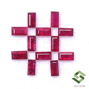 May include: A collection of 14 red ruby gemstones, cut in a rectangular shape, arranged in a grid pattern on a white surface.