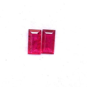 Puede incluir: Dos piedras preciosas de rubí rectangulares, cada una de color rojo y talla facetada.