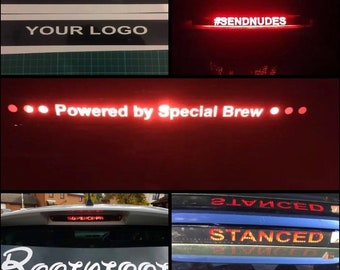 May include: A red and white car window decal with the text "#SENDNUDES" in red. The decal is illuminated from behind, making the text glow. The decal is on a black background.