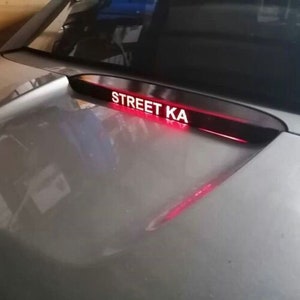 May include: A rear window spoiler with a red light strip and the text "STREET KA" in white letters.