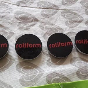 May include: Four black round stickers with a silver rim. Each sticker has the word "rotiform" printed in red.