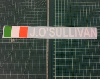 May include: White vinyl sticker with the text "J. O'SULLIVAN" in white letters. The sticker also features a small Irish flag with green, white, and orange colors.