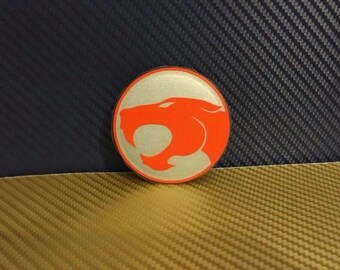May include: A round, silver-colored sticker with a red panther head silhouette. The panther is facing right and has a fierce expression.