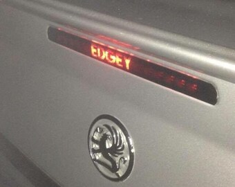 May include: A silver car with a red brake light that says "EDGEY" and a silver Vauxhall badge.