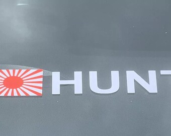 May include: A white sticker with the word "HUNT" in large, bold letters. A red and white Japanese flag is to the left of the word.