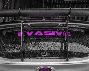 May include: A silver car with a large black spoiler and a pink "EVASIVE" sticker on the rear window.