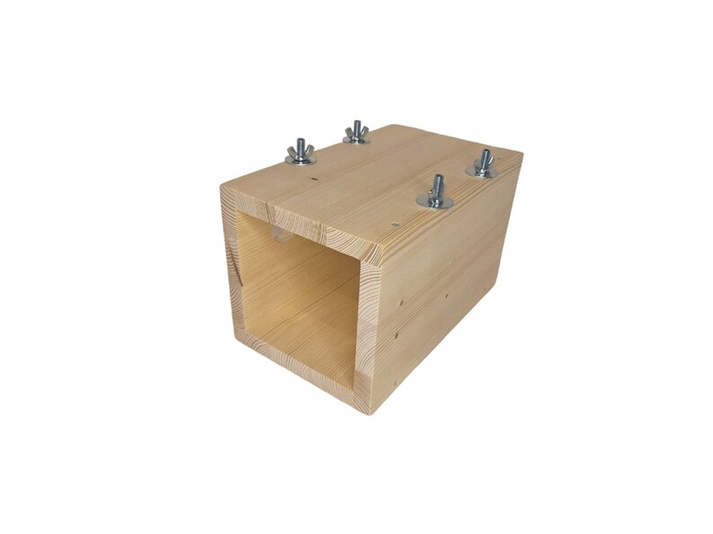 May include: A wooden box with a square opening, secured with four metal screws. The box is made of light-colored wood and has a natural finish.