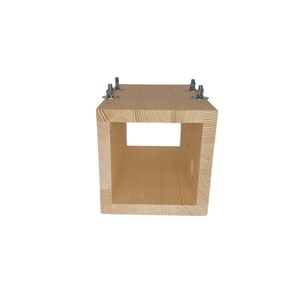 May include: A wooden box with a square opening in the front. The box is made of light wood and has four metal screws on the top.