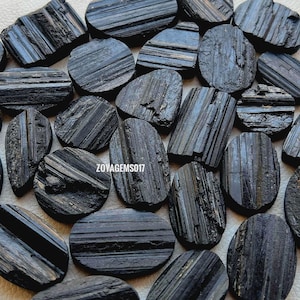 以下が含まれることがあります： 縞模様のある黒トルマリンの石の集まり。シュールとも呼ばれます。石は楕円形で、滑らかで磨かれた仕上げになっています。