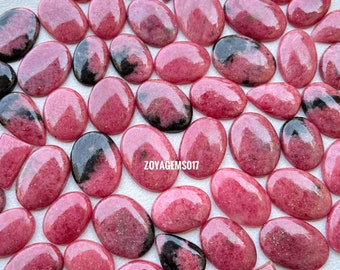 Puede incluir: Una colección de 35 cabujones de piedras preciosas rosas y negras. Los cabujones son de varias formas y tamaños, incluyendo ovalados, de pera y cuadrados. Las piedras son una mezcla de rosa y negro, con algunas que tienen un patrón negro más pronunciado.