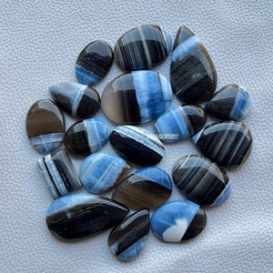 May include: A collection of 16 blue and black banded opal cabochons. The cabochons are various shapes and sizes, with some having a more pronounced blue color than others.