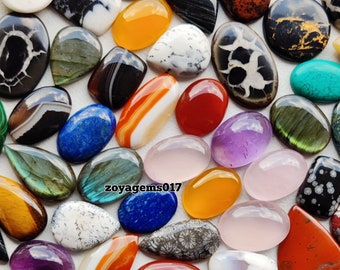 May include: Assortment of colorful, polished gemstone cabochons in various shapes and sizes. The cabochons are arranged on a white surface. Some of the gemstones include tiger's eye, amethyst, agate, and turquoise.