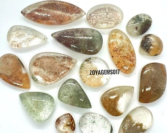 May include: A collection of 16 teardrop-shaped, translucent, green, brown, and orange gemstone cabochons. The cabochons have a variety of inclusions and patterns. The text "ZOYAGEMS017" is visible in the image.