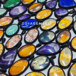 May include: A collection of colorful oval-shaped gemstone pendants with black cord. The stones are various shades of yellow, green, purple, blue, and brown. The text "ZOYAGEMS017" is visible in the center of the image.
