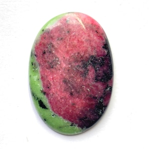 May include: An oval-shaped polished gemstone featuring a vibrant mix of colours including bright lime green, deep magenta pink, and dark black inclusions. The surface is smooth and reflective, showcasing a natural mottled pattern throughout the stone.