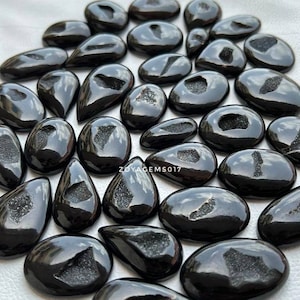 May include: A collection of black agate cabochons with a variety of shapes and sizes. The cabochons have a smooth, polished surface and a natural, crystal-like pattern.