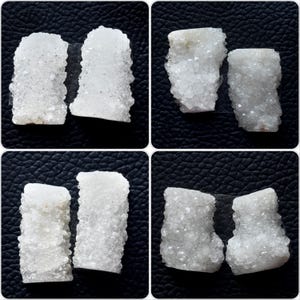 May include: Four sets of white quartz crystal clusters are displayed against a black background. Each cluster has a rough, textured surface with visible crystalline structures. The clusters vary slightly in shape and size, showcasing natural formations.