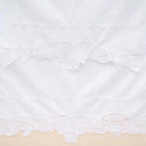 May include: Two white cotton handkerchiefs with delicate lace trim. The handkerchiefs are embroidered with small white dots and a simple line design.
