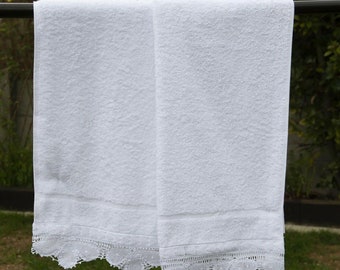 May include: Two white towels with lace trim hanging on a clothesline. The towels are made of a soft, absorbent material and are perfect for drying off after a shower or bath.
