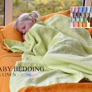May include: A child sleeps on a bed with a light green linen blanket and a mustard yellow linen sheet. The text "BABY BEDDING 100% LINEN" is visible on the sheet. A swatch card with various colors of linen fabric is shown in the upper right corner of the image. The text "ALL COLORS" is visible on the right side of the image.