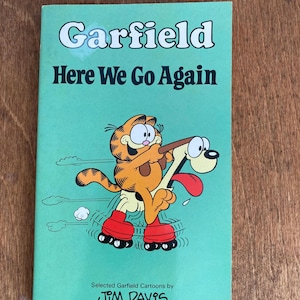 May include: A vintage Garfield comic book titled "Here We Go Again." The cover is a light green with the title in white and black. Garfield, an orange cat, is depicted roller skating with a dog. The book is by Jim Davis.