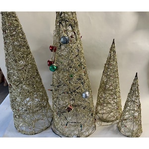 May include: Four gold wire Christmas trees decorated with tinsel and ornaments. The trees are different sizes and are arranged in a row.