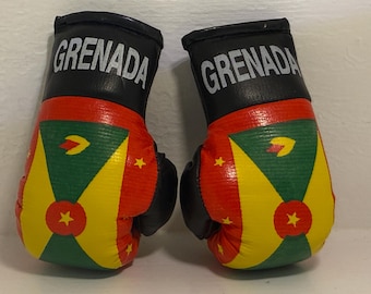 May include: A pair of black boxing gloves with the word "GRENADA" printed on the top of each glove. The gloves are decorated with the flag of Grenada.
