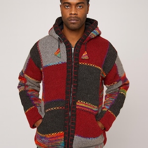 May include: A hooded patchwork jacket in shades of red, gray, and black. The jacket features a full zipper, pockets, and colorful embroidered details. The design incorporates geometric shapes and a cozy, textured knit.