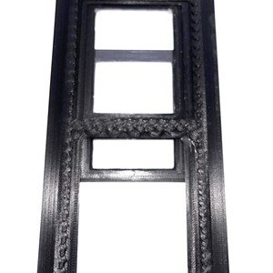 May include: A black rectangular frame with three open sections. The frame has a decorative, textured border. The image is a close-up shot of the frame against a white background.
