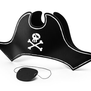 Könnte beinhalten: Ein schwarzer Piratenhut mit einem weißen Totenkopf- und gekreuzten Knochen-Emblem und einer passenden Augenklappe. Der Hut hat eine gebogene Krempe und eine weiße Kontur. Die Augenklappe ist mit einem dünnen schwarzen Faden verbunden.