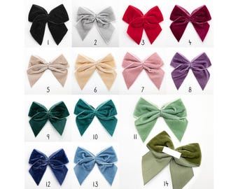 Puede incluir: Surtido de 14 lazos para el pelo de terciopelo en varios colores, incluyendo negro, gris, rojo, morado, verde, azul y beige. Cada lazo tiene un ribete blanco alrededor de los bordes.
