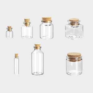 Könnte beinhalten: Sechs durchsichtige Glasflaschen mit Korkstopfen. Die Flaschen sind in verschiedenen Größen und Formen, darunter rund, quadratisch und zylindrisch.