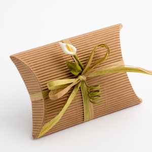 Op de afbeelding: Een bruine kartonnen geschenkdoos met een groen lint en een witte bloem. De doos is gebonden met een strik en de bloem is een calla.