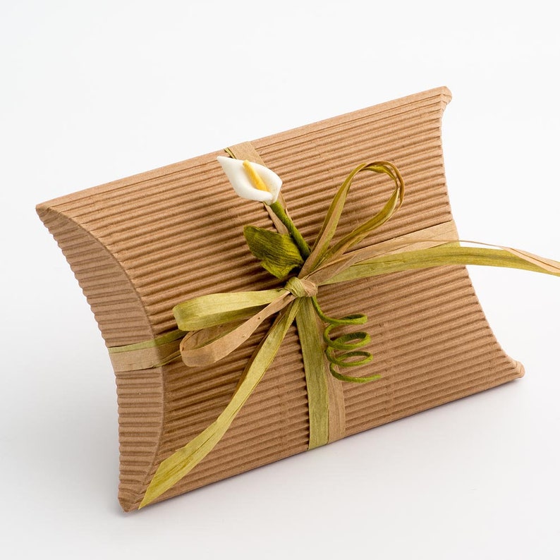 Op de afbeelding: Een bruine kartonnen geschenkdoos met een groen lint en een witte bloem. De doos is gebonden met een strik en de bloem is een calla.