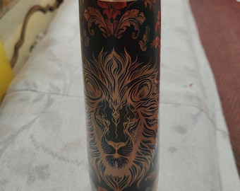 May include: A cylindrical metal water bottle with a metallic copper-coloured screw-top lid. The body of the bottle is black and features a detailed, engraved-style illustration of a lion's face in copper tones, surrounded by ornate floral patterns.