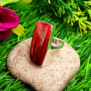 Puede incluir: Un anillo de plata con una piedra rectangular roja.