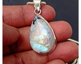 May include: A teardrop-shaped rainbow moonstone pendant set in sterling silver. The stone displays a vibrant iridescent sheen with flashes of blue, green, and gold.
